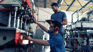 Two people operating a machine in a factory